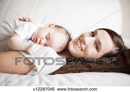 Stock Photograph - Mother embracing sleeping baby girl (2-5 months) . Fotosearch