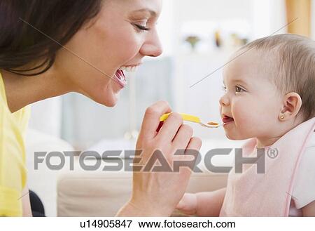 Stock Photo - Mother feeding baby daughter (6-11 months). Fotosearch