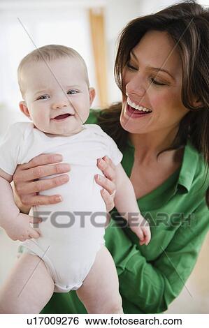 Mother holding baby daughter (6-11 months) View Large Photo Image Stock Photograph - Mother holding baby daughter (6-11 months). Fotosearch
