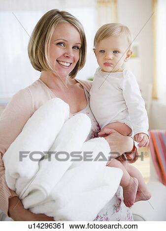 Stock Image - Mother holding son (6-11 months) and laundry. Fotosearch