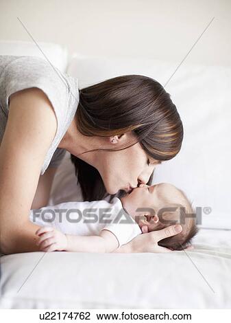 Stock Image - Mother kissing baby girl (2-5 months). Fotosearch