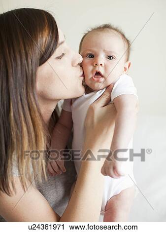 Stock Image - Mother kissing baby girl (2-5 months). Fotosearch