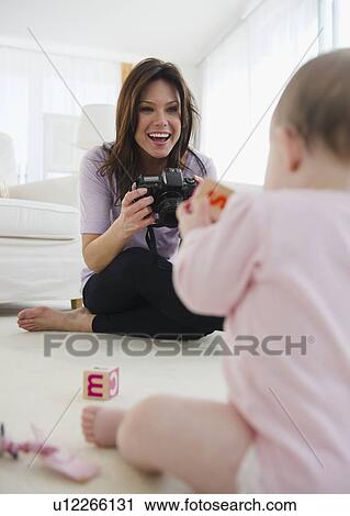 Stock Image - Mother photographing baby daughter (6-11 months). Fotosearch