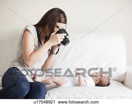 Stock Image - Mother photographing baby girl (2-5 months). Fotosearch