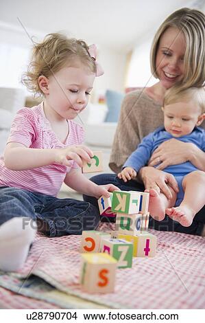 Mother playing with children (2-3, 6-11 months) at home View Large Photo Image Picture - Mother playing with children (2-3, 6-11 months) at home. Fotosearch