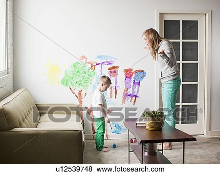 Stock Photo - Mother telling toddler boy (2-3) off for painting on walls. Fotosearch