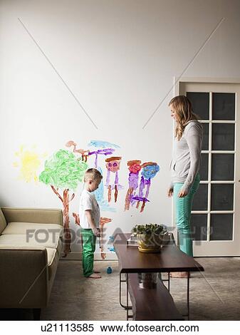 Stock Photography - Mother telling toddler boy (2-3) off for painting on walls. Fotosearch
