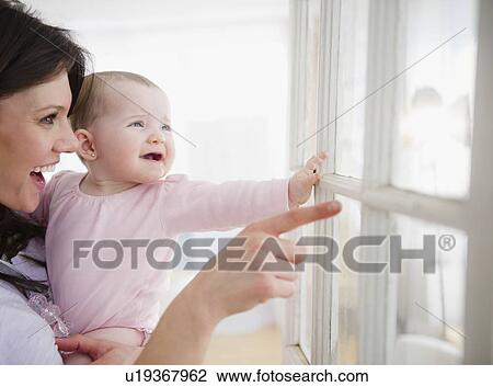 Mother with baby daughter (6-11 months) looking through window View Large Photo Image Stock Image - Mother with baby daughter (6-11 months) looking through window. Fotosearch