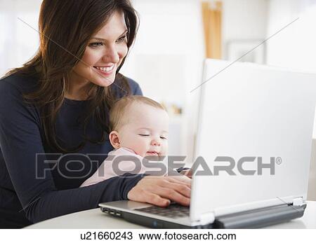 Mother with baby daughter (6-11 months) using laptop View Large Photo Image Stock Image - Mother with baby daughter (6-11 months) using laptop. Fotosearch