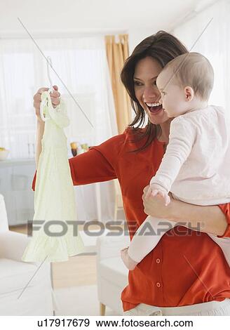 Stock Photo - Mother with baby daughter (6-11 months) holding dress. Fotosearch