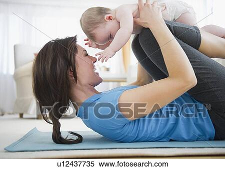 Mother with baby daughter (6-11 months) practicing yoga View Large Photo Image Stock Photography - Mother with baby daughter (6-11 months) practicing yoga. Fotosearch