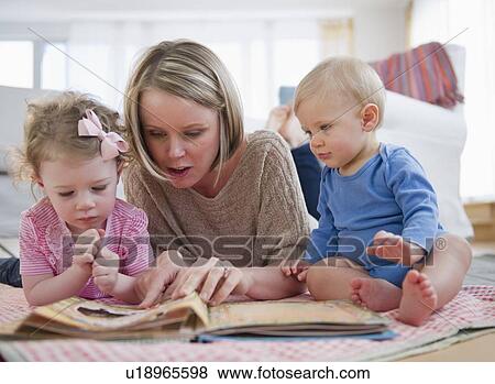 Stock Photo - Mother with children (2-3, 6-11 months) reading book. Fotosearch