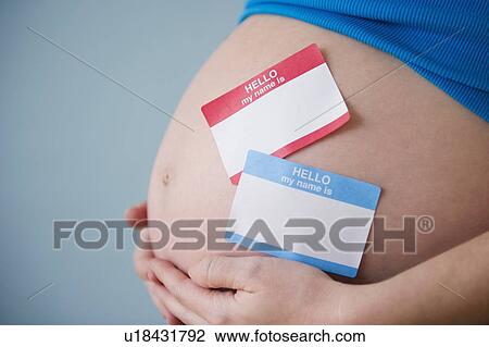 Stock Image - Name tags on belly of pregnant woman. Fotosearch