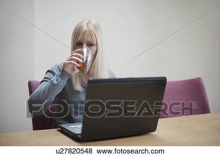 Netherlands, Goirle, Young woman relaxing in front of laptop and drinking tea View Large Photo Image Stock Photo - Netherlands, Goirle, Young woman relaxing in front of laptop and drinking tea. Fotosearch