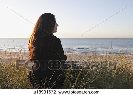 Stock Image - Netherlands, Zeeland, Haamstede, Woman relaxing on sand dune. Fotosearch