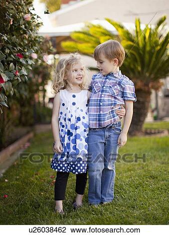 Stock Image - Outdoor portrait of girl (4-5) and boy (6-7) . Fotosearch