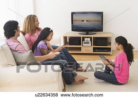 Parents with daughters (10-13) watching tv View Large Photo Image Stock Photo - Parents with daughters (10-13) watching tv. Fotosearch