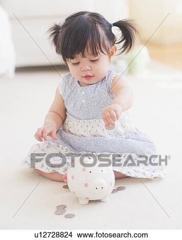 Portrait of baby girl (12-17 months) playing with piggy bank View Large Photo Image Picture - Portrait of baby girl (12-17 months) playing with piggy bank. Fotosearch