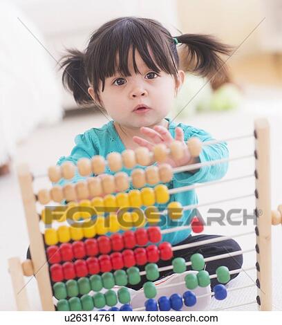 Stock Image - Portrait of baby girl (12-17 months) playing with abacus. Fotosearch