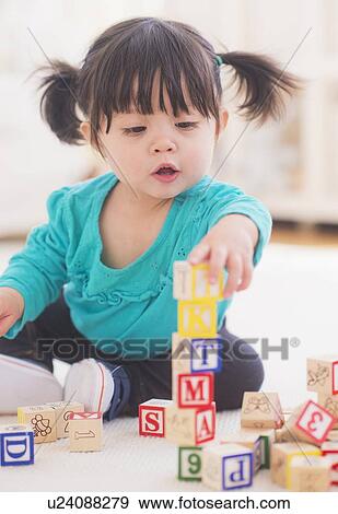 Stock Photo - Portrait of baby girl (12-17 months) playing alphabet blocks. Fotosearch
