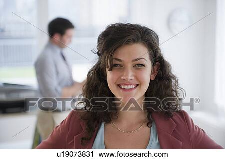 Stock Image - Portrait of business woman, business man in background. Fotosearch