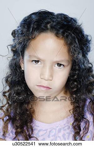 Stock Image - Portrait of confused girl (8-9), studio shot. Fotosearch