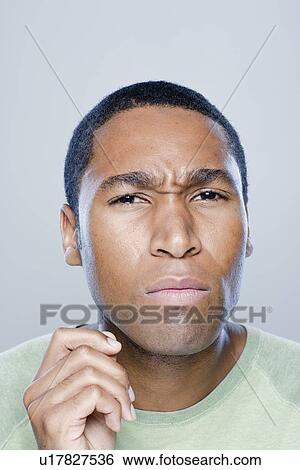 Stock Photograph - Portrait of confused young man, studio shot. Fotosearch