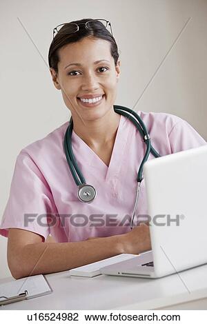 Portrait of female doctor working on laptop View Large Photo Image Stock Image - Portrait of female doctor working on laptop. Fotosearch