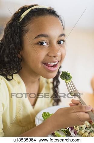 Picture - Portrait of girl (12-13) eating dinner. Fotosearch