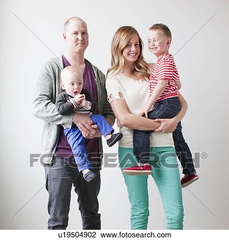 Stock Image - Portrait of happy young family with two boys (12-17 months, 2-3). Fotosearch