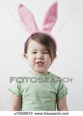 Stock Image - Portrait of mixed-race girl (2-3) wearing bunny ears. Fotosearch