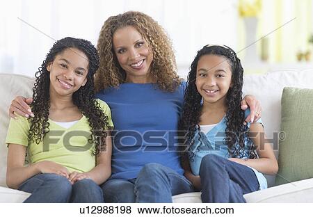 Portrait of mother with daughters (10-13) sitting on sofa View Large Photo Image Stock Photo - Portrait of mother with daughters (10-13) sitting on sofa. Fotosearch