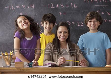 Stock Image - Portrait of pupils (10-11, 12-13) and teacher with blackboard in background. Fotosearch