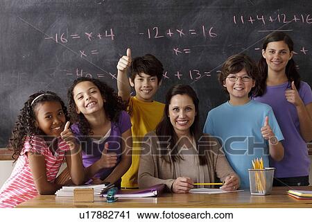 Stock Image - Portrait of pupils (10-11, 12-13) and teacher with blackboard in background. Fotosearch