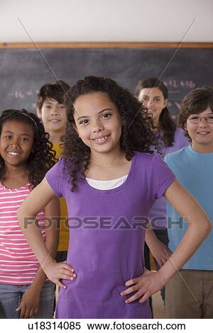 Stock Photography - Portrait of pupils (10-11, 12-13) with blackboard in background. Fotosearch