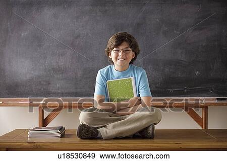 Portrait of schoolboy (10-11) cross-legged sitting in front of blackboard View Large Photo Image Stock Photo - Portrait of schoolboy (10-11) cross-legged sitting in front of blackboard. Fotosearch