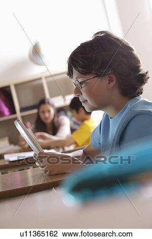 Stock Image - Portrait of schoolboy (10-11) with digital tablet. Fotosearch