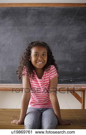 Portrait of schoolgirl (10-11) sitting in front of blackboard View Large Photo Image Stock Image - Portrait of schoolgirl (10-11) sitting in front of blackboard. Fotosearch