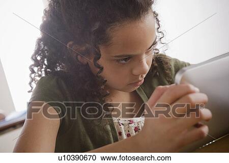 Stock Image - Portrait of schoolgirl (10-11) with digital tablet. Fotosearch