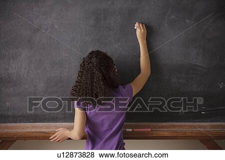 Stock Photo - Portrait of schoolgirl (10-11) writing on blackboard. Fotosearch