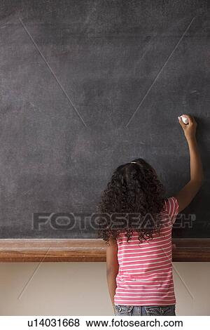 Stock Photo - Portrait of schoolgirl (10-11) writing on blackboard. Fotosearch