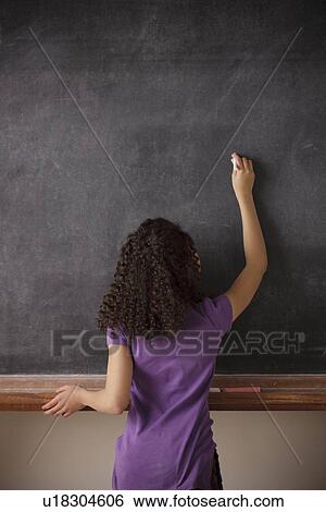 Stock Photograph - Portrait of schoolgirl (10-11) writing on blackboard. Fotosearch