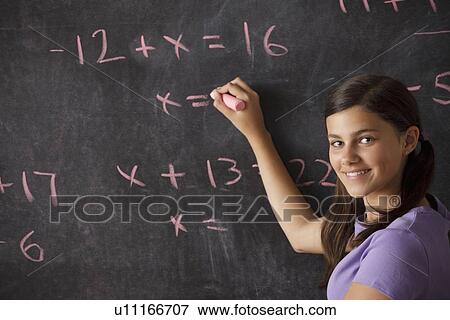 Stock Photo - Portrait of schoolgirl (12-13) standing in front of blackboard during math classes. Fotosearch