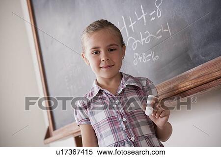Stock Photography - Portrait of schoolgirl holding chalk. Fotosearch