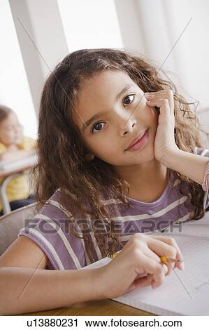 Stock Image - Portrait of schoolgirl holding pencil. Fotosearch