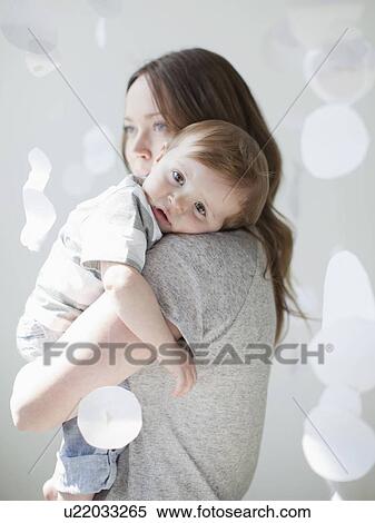 Stock Photography - Portrait of serene young woman embracing baby boy (6-11 months). Fotosearch