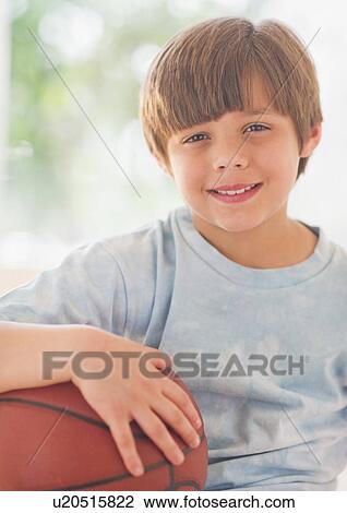 Stock Image - Portrait of smiling boy (10-11 years) with basketball ball. Fotosearch