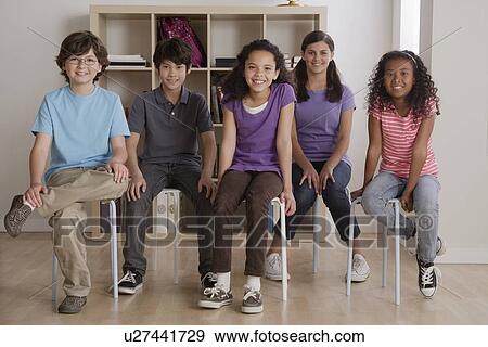 Stock Photo - Portrait of smiling pupils sitting in classroom. Fotosearch