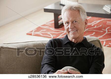 Portrait of smiling senior man sitting on sofa View Large Photo Image Stock Photograph - Portrait of smiling senior man sitting on sofa. Fotosearch