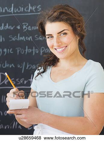 Portrait of smiling waitress against blackboard with menu View Large Photo Image Stock Photo - Portrait of smiling waitress against blackboard with menu. Fotosearch